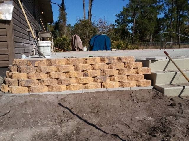 Stacked block retaining wall beside pool steps