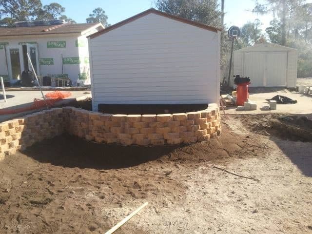 Curved retaining wall surrounding a backyard shed
